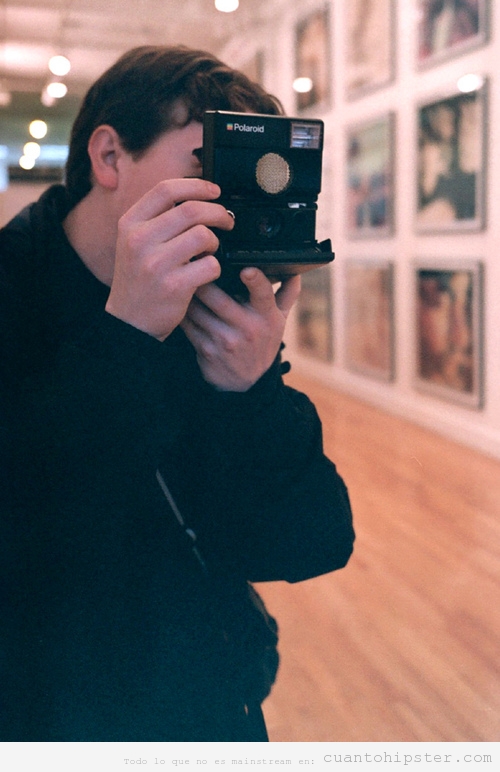 Chico hipster haciendo fotos con una Polaroid en un museo