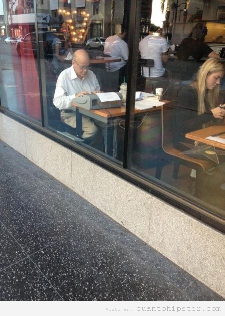 Abuelo hipster con maquina escribir antigua en una cafetería