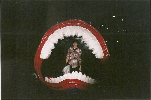Chico hipster dentro de una boca grande con dientes