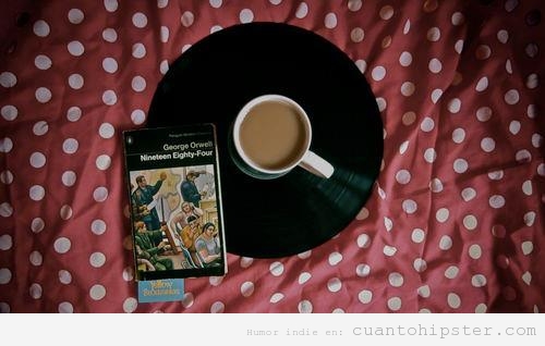 Imagen bonita indie y hipster de una taza de café posada sobre un vinilo y la novela 1984 de Orwell
