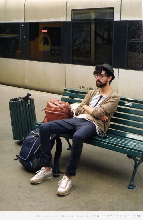 Chico hipster esperando en el banco de una estación de tren