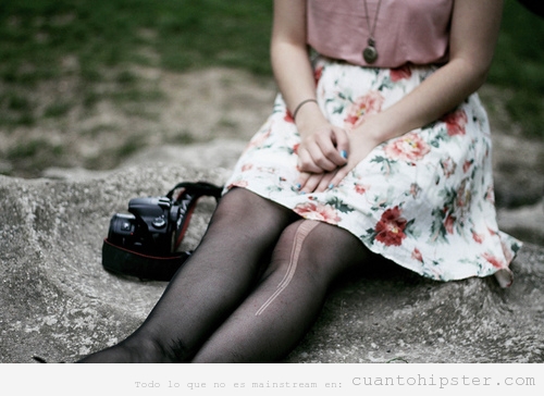 Imagen de una chica con ropa vintage, las medias rotas y cámara reflex