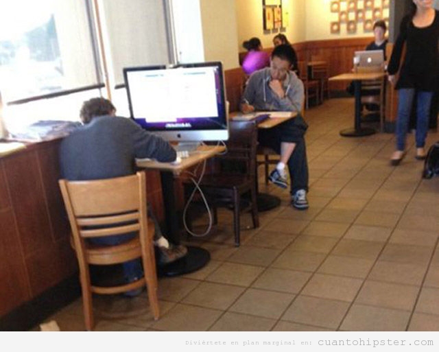 Imagen graciosa de un chico con un Mac grande en cafetería