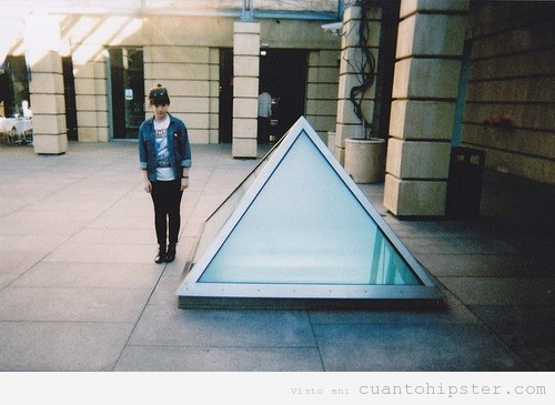 Hipster posando al lado de una claraboya con forma de triángulo