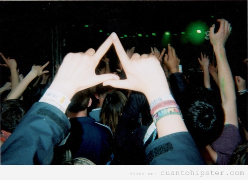 Imagen de un triángulo formado con las manos en un concierto