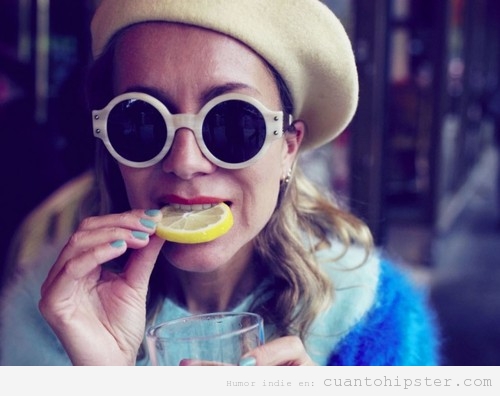 Chica con boina, gafas de sol comiendo un limón, look beatnik