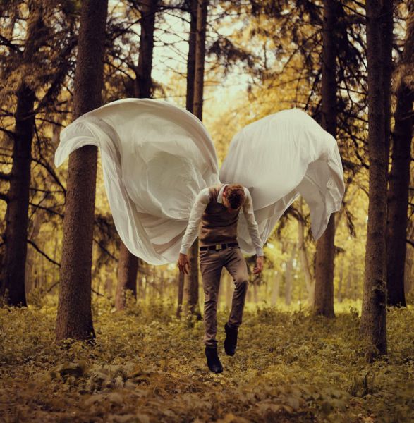 Foto bonita de un chico volando con unas alas de sábanas