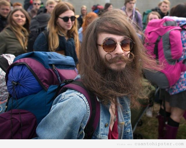 Chico look hippie hipster con una mochila en un festival indie