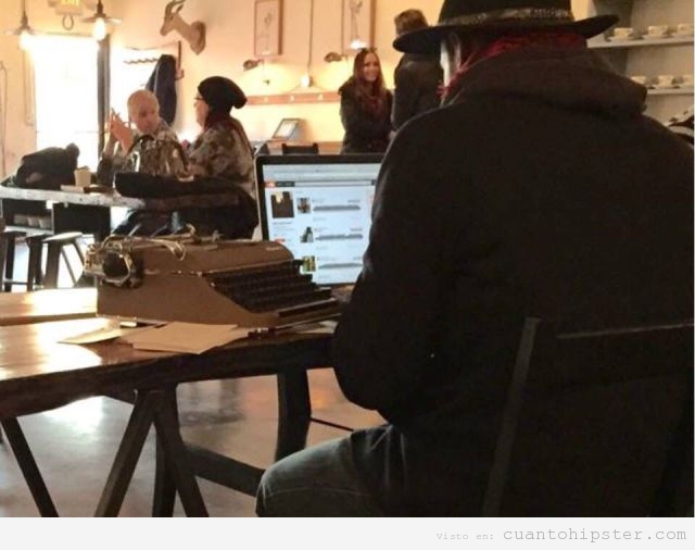 Hipster en una cafetería con la máquina de escribir