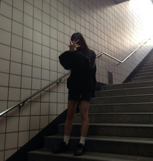 Foto de una chica con look grunge bajando las escaleras del metro