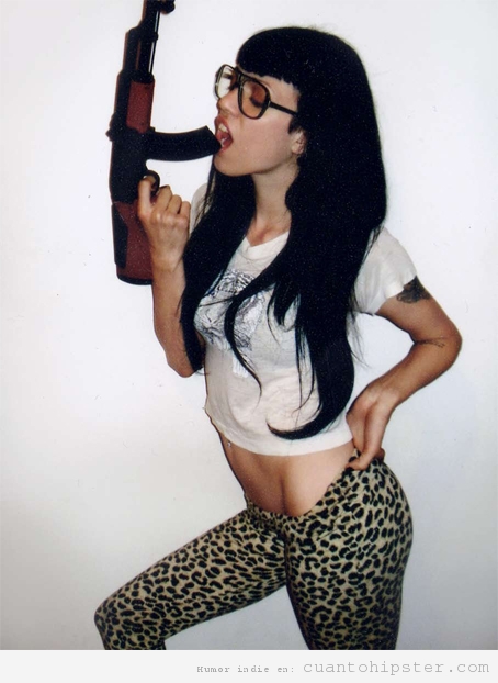 Chica con gafas hipster y mallas de leopardo lame una escopeta