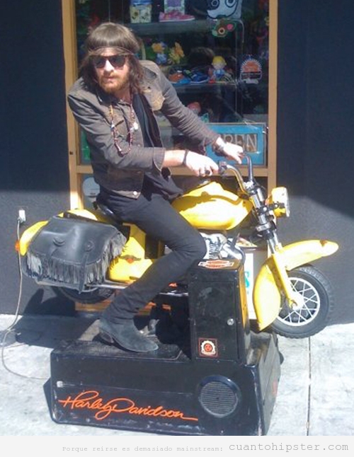 Chico hipster montado en una harley de juguete en la calle
