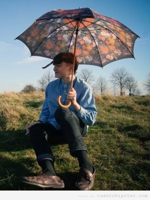 Retrato bucólico de un hipster en el campo con paraguas flores