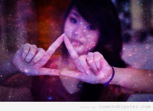 Chica asiática hace el triángulo hipster con la mano y fondo imagen cósmico
