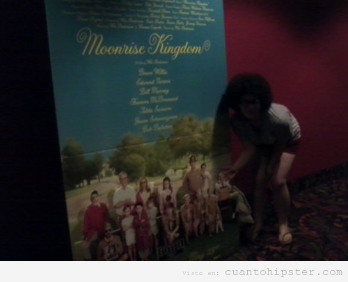 Chica moderna o hipster haciéndose una foto en el cine con un cartel de Moonrise Kingdom, la nueva de Wes Anderson