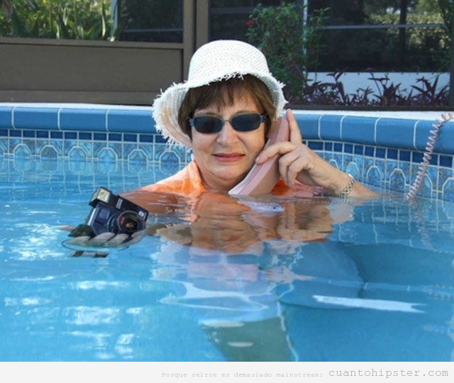 Abuela hipster en la piscina con ropa, teléfono  cámara antigua