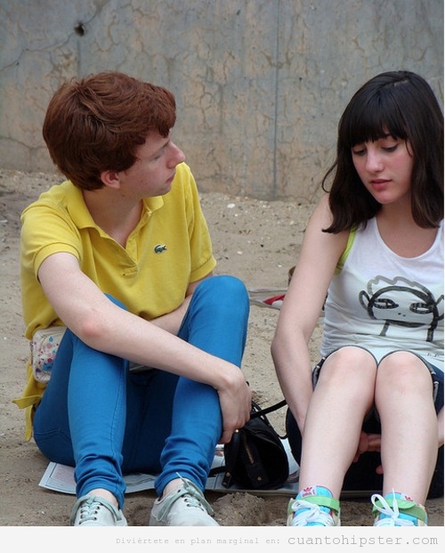 Chico y chica adolescentes hipsters sentados en el suelo