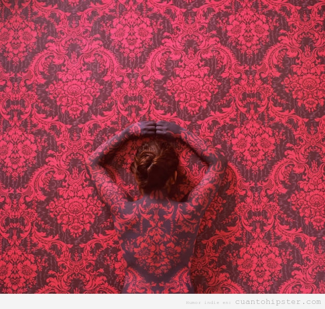 Mujer con el cuerpo pintado para camuflarse con un papel pintado de pared