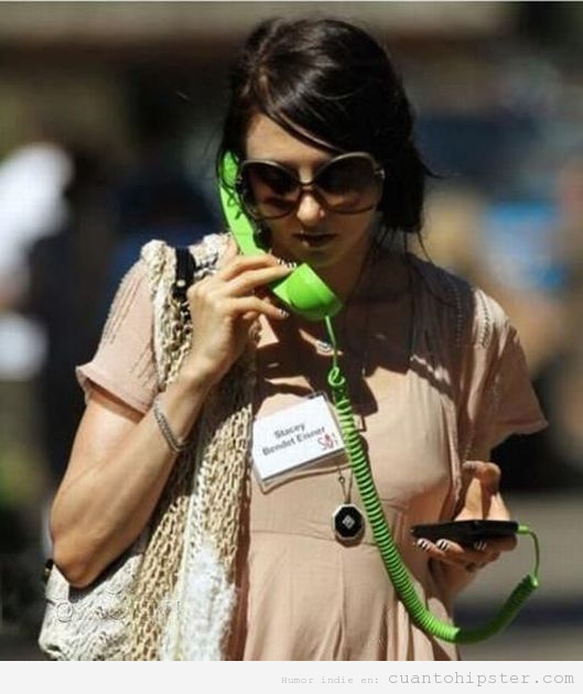 Chica hipster con el gadget de teléfono retro como auricular para su iphone