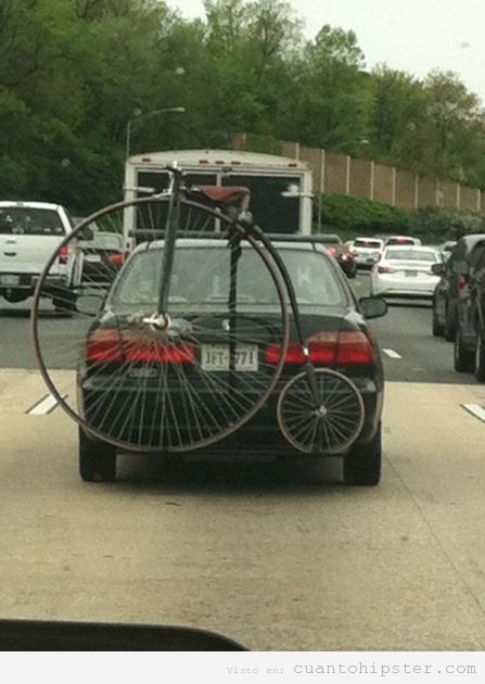 Bicicleta antigua de rueda grande atada a un coche