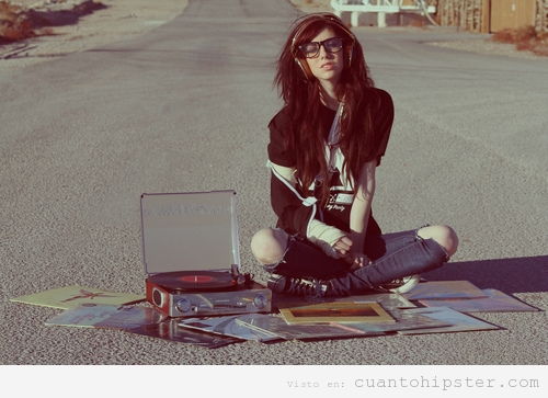 Chica hipster sentada en el asfalto escuchando vinilos