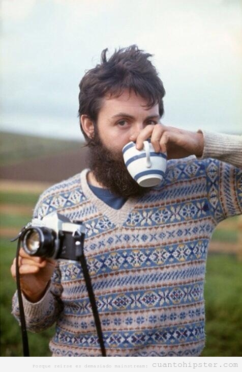 Imagen antigua de Paul McCartney de joven con barba, jersey hipster y cámara de fotos antigua