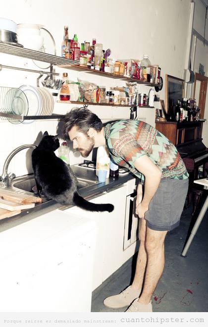 Foto de un chico hipster y un gato mirándose
