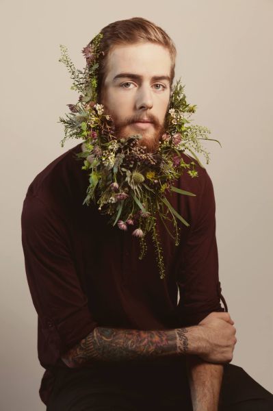 Imagen de un chico hipster con la barba larga llena de flores
