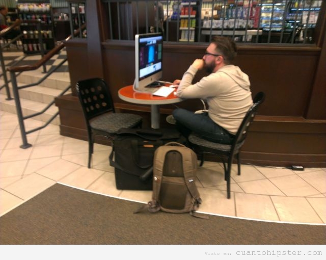 Foto graciosa de un hipster trabajando cn el iMac en la cafetería