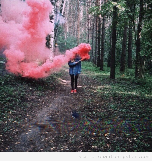 Foto de una chica con una bengala de humo en el bosque